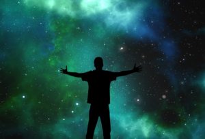 Person in silhouette opening arms to universe